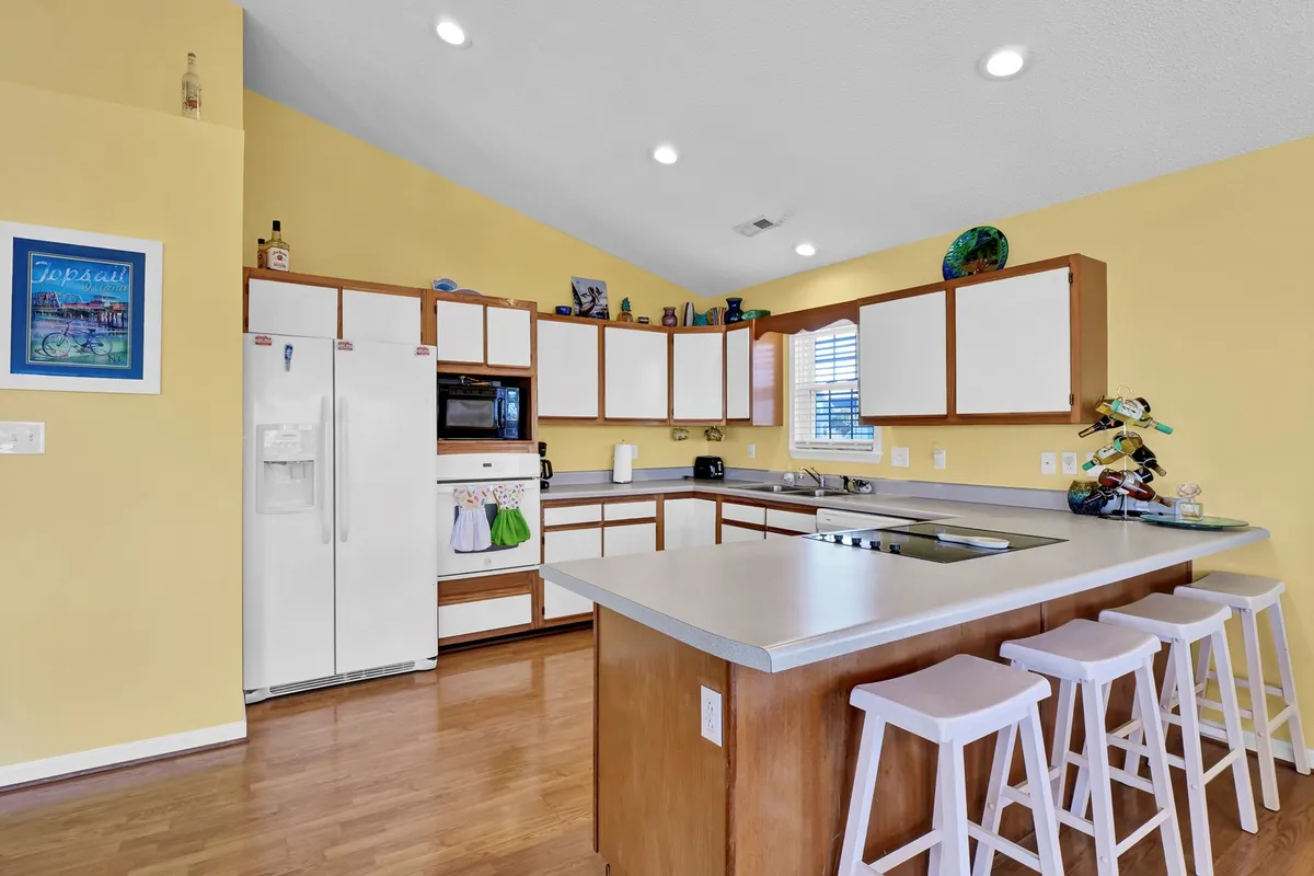 A view of a modern kitchen with a central island, colorful walls, plenty of appliances, and lively decorative touches. The space is clearly designed for cooking, entertaining, and connecting with others, embodying the well-equipped kitchen described in the section.