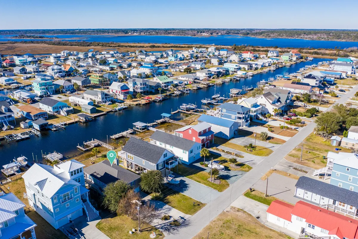 This image captures a lively canal lined with colorful houses, a marina, and sparkling blue water. The scene suggests a neighborhood with easy access to both local shops and water-based activities, evoking a sense of exploration and community charm.