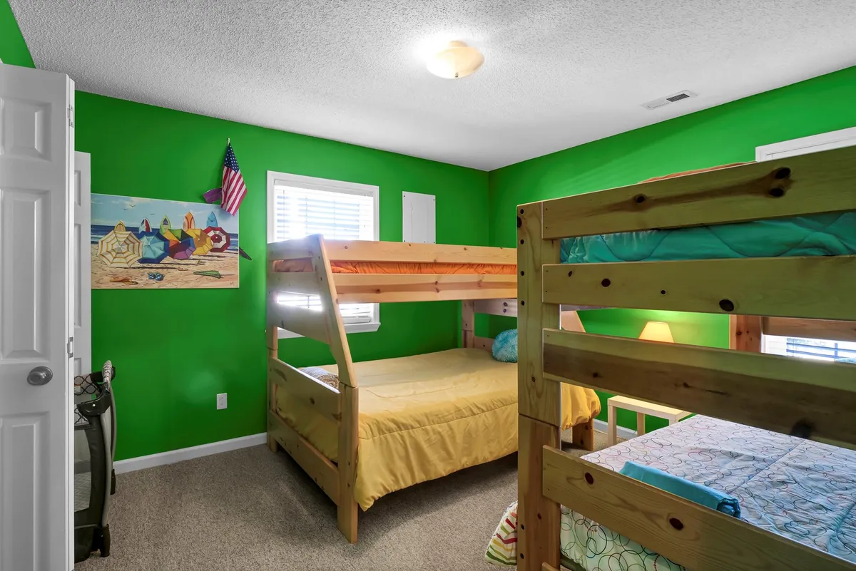 A cheerful, brightly colored kids' bedroom featuring fun bunk beds, colorful wall art, and lively green walls. The space is designed for play, storytelling, and sleepovers, capturing the fun and togetherness of a family getaway.