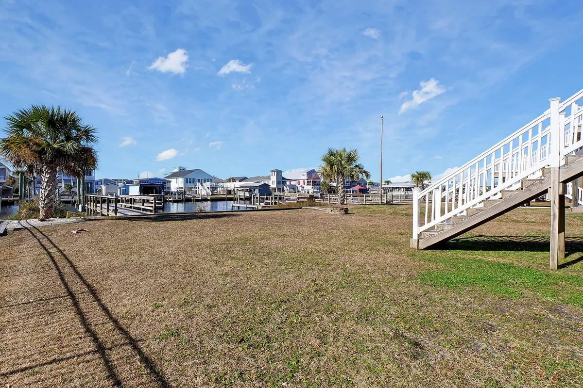 A lush canal scene with palm trees, a pedestrian walkway, and inviting coastal houses lining the waterfront. The tranquil blue water and greenery create a relaxing outdoor atmosphere.