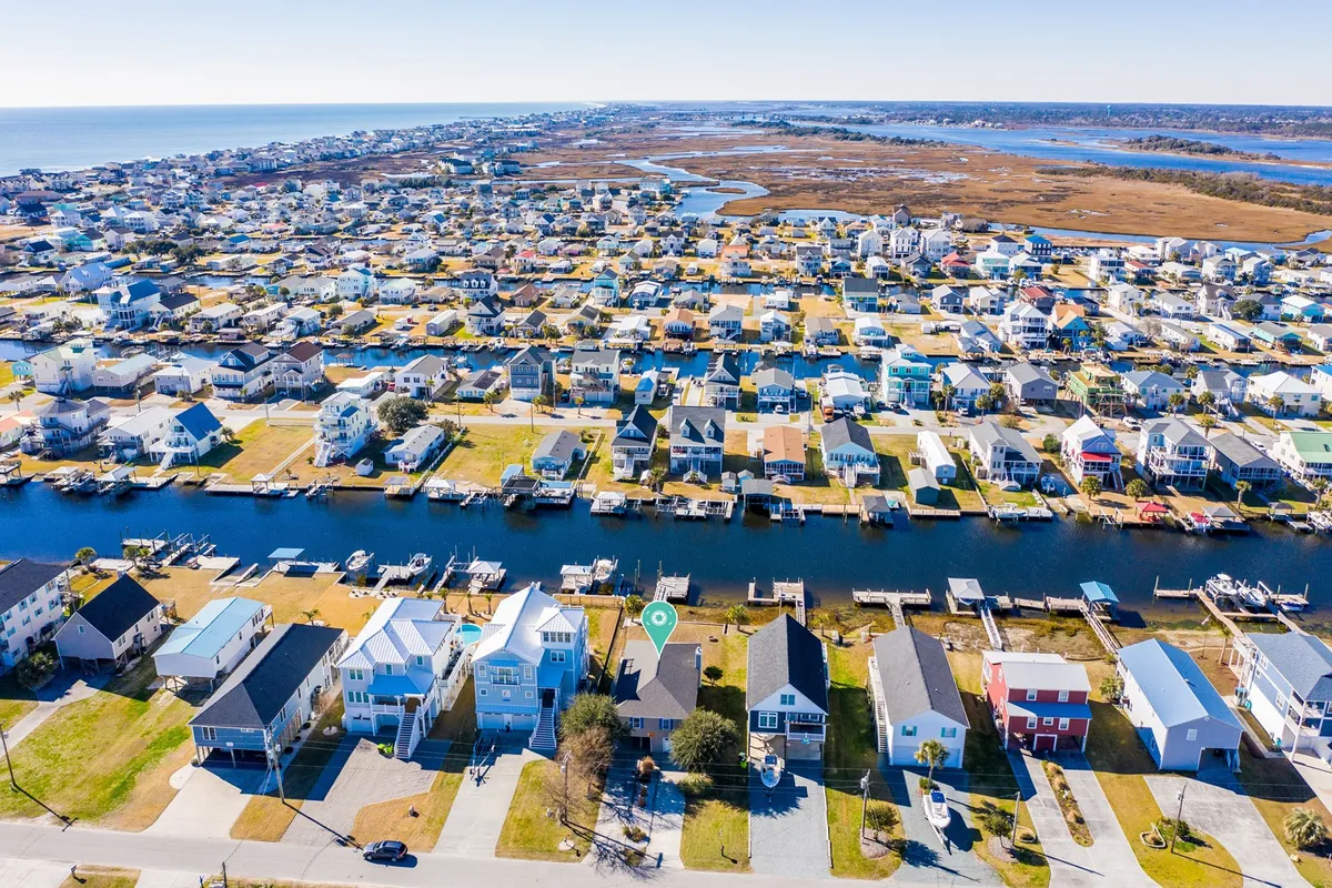 A wide view of waterfront properties and canals, with a clear look at the neighborhood layout and distant views of the ocean. The scene conveys the relaxed, community-oriented spirit of Surf City and offers visual context for its easy access to both nature and attractions.