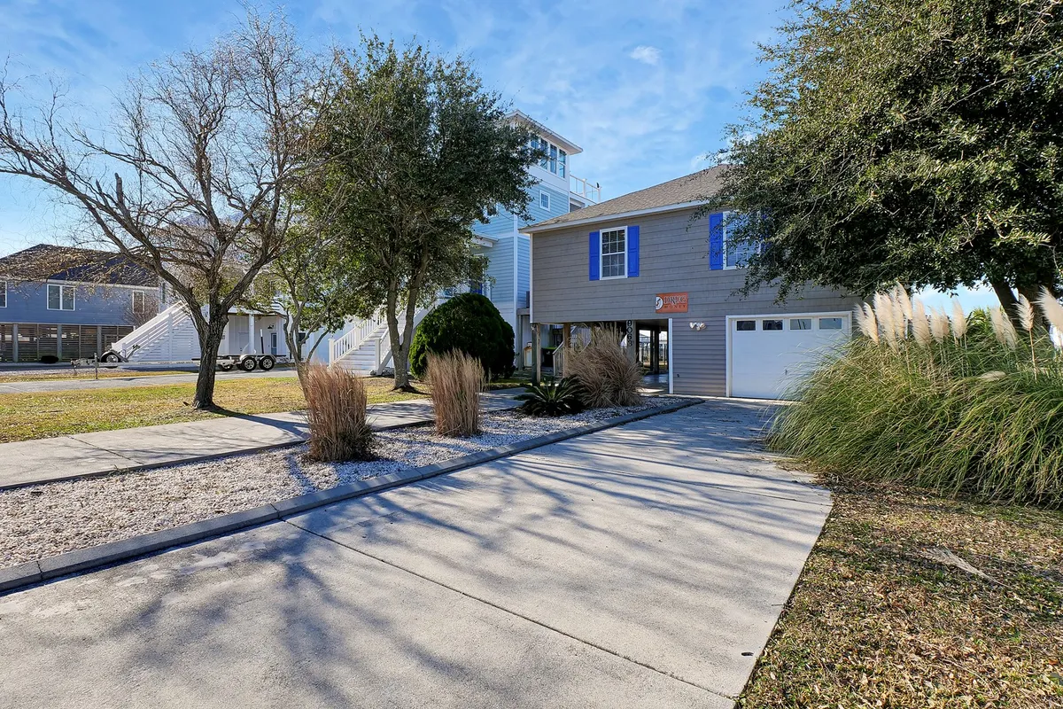 The main house is shown with attractive landscaping and a welcoming driveway. The exterior exudes warmth and hospitality, with space for gathering outdoors, relaxing in the yard, and easy access to nearby attractions.